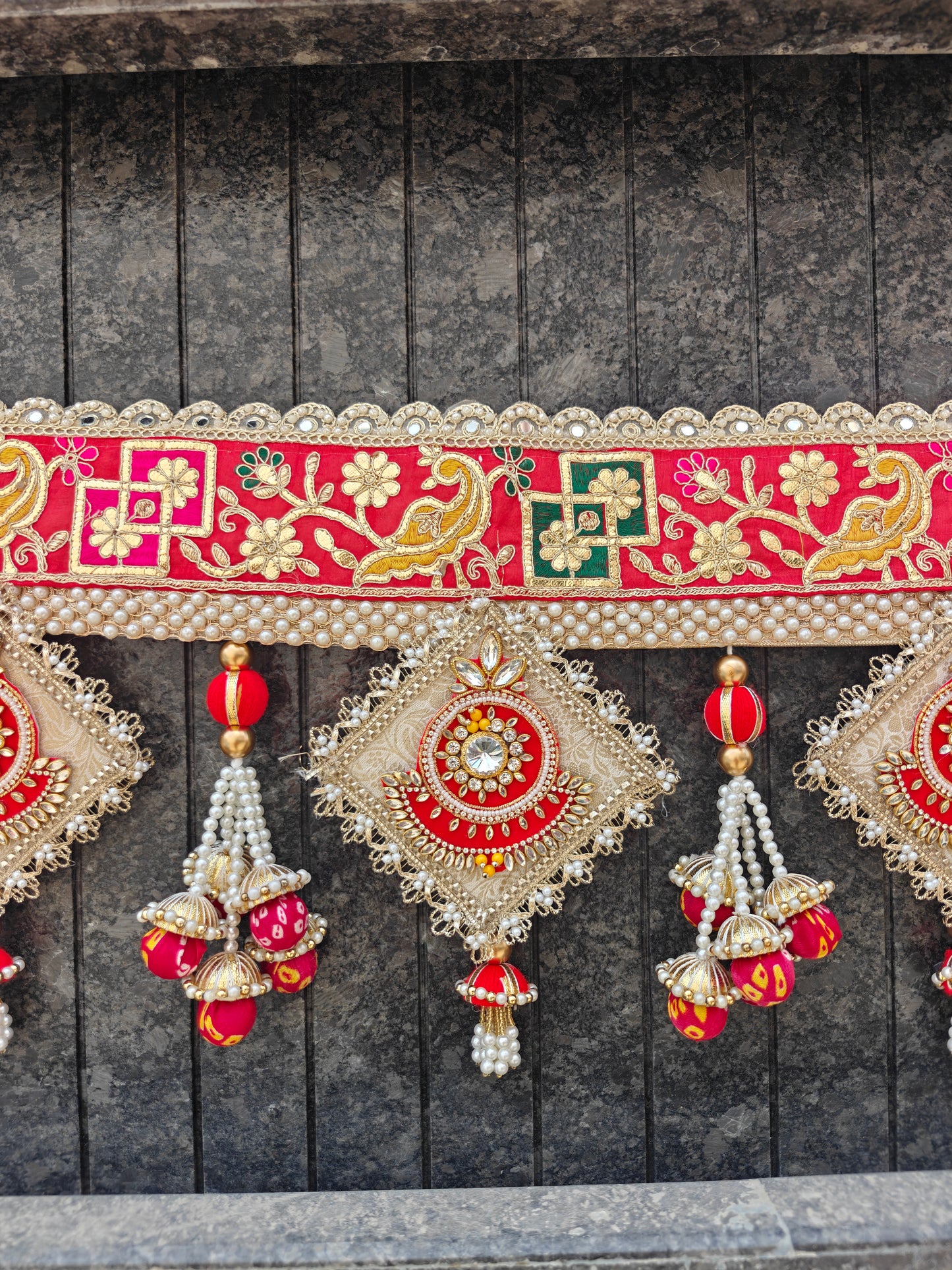 "Red gold gota patti bandhanwar close-up with kundan diamond pendant and pearl jhumki tassel"