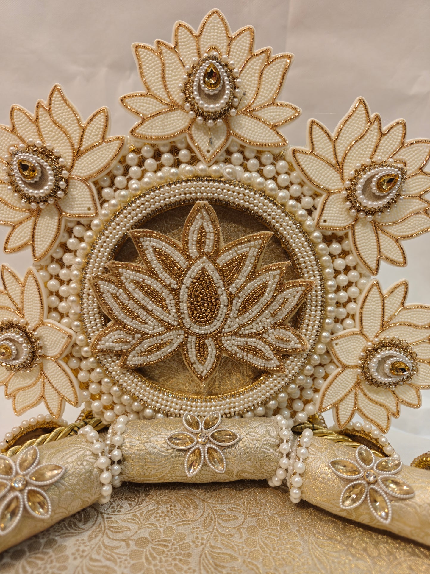Close-up of ivory lotus garden Singhaasan backdrop for Ladoo Gopal — beaded lotus centre medallion surrounded by five ivory gold lotus flowers with pearl garlands by The Wedding Station