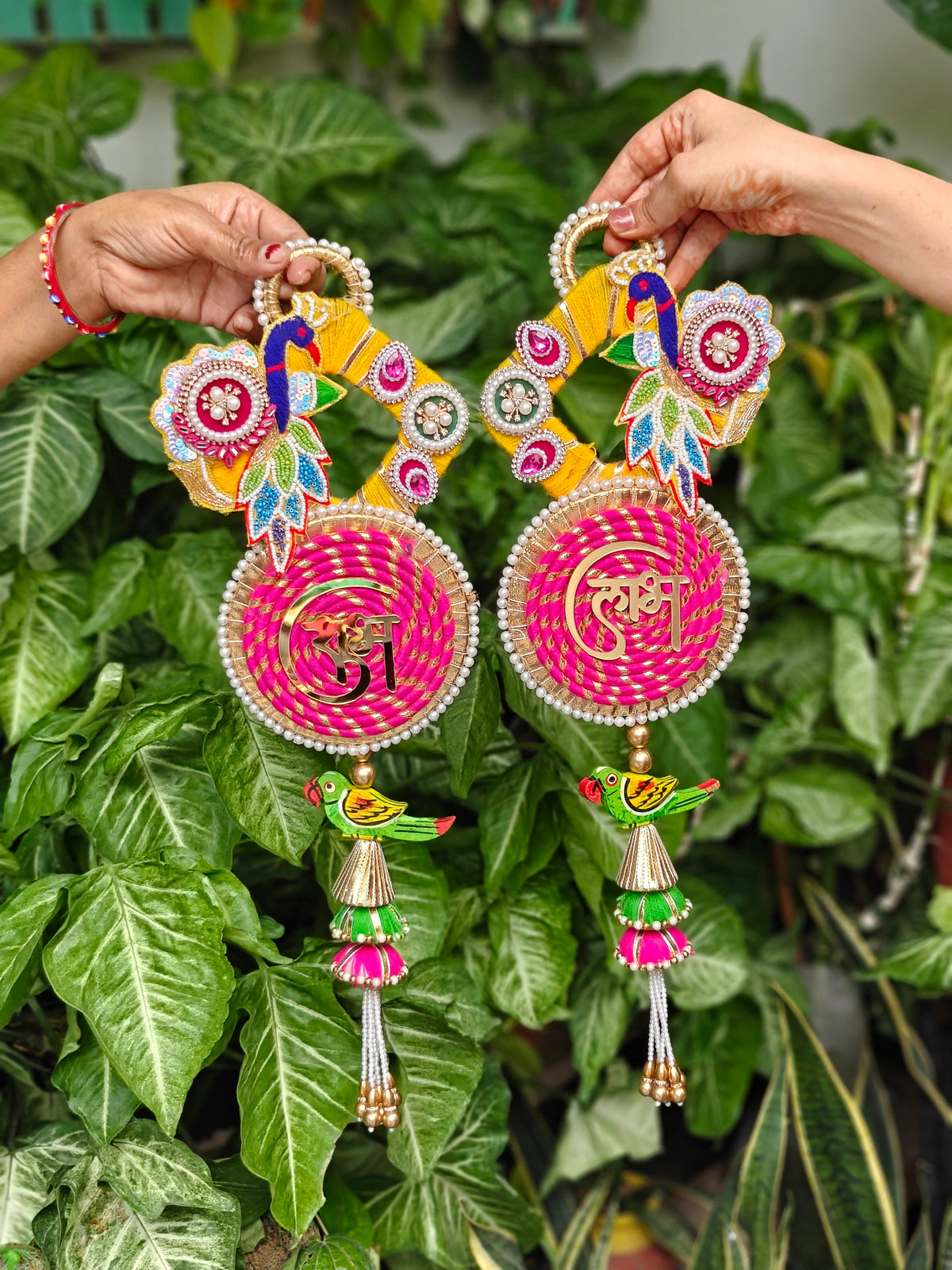 Handcrafted pink and yellow Peacock Shubh Laabh hanging with traditional Indian festive embellishments, 20 inches x 7 inches