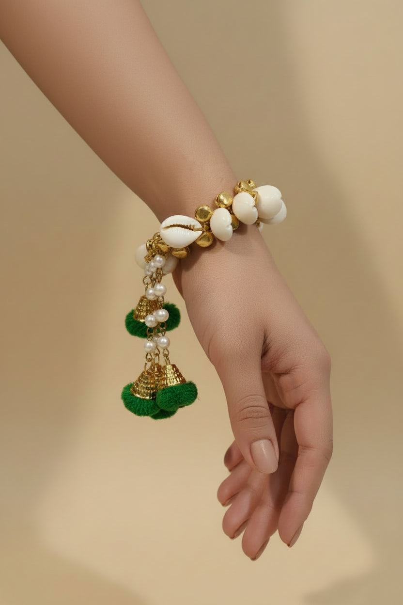 shell bracelet with gold accents, pearl chain danglers, and green pom poms — Haldi and Mehendi jewellery by The Wedding Station