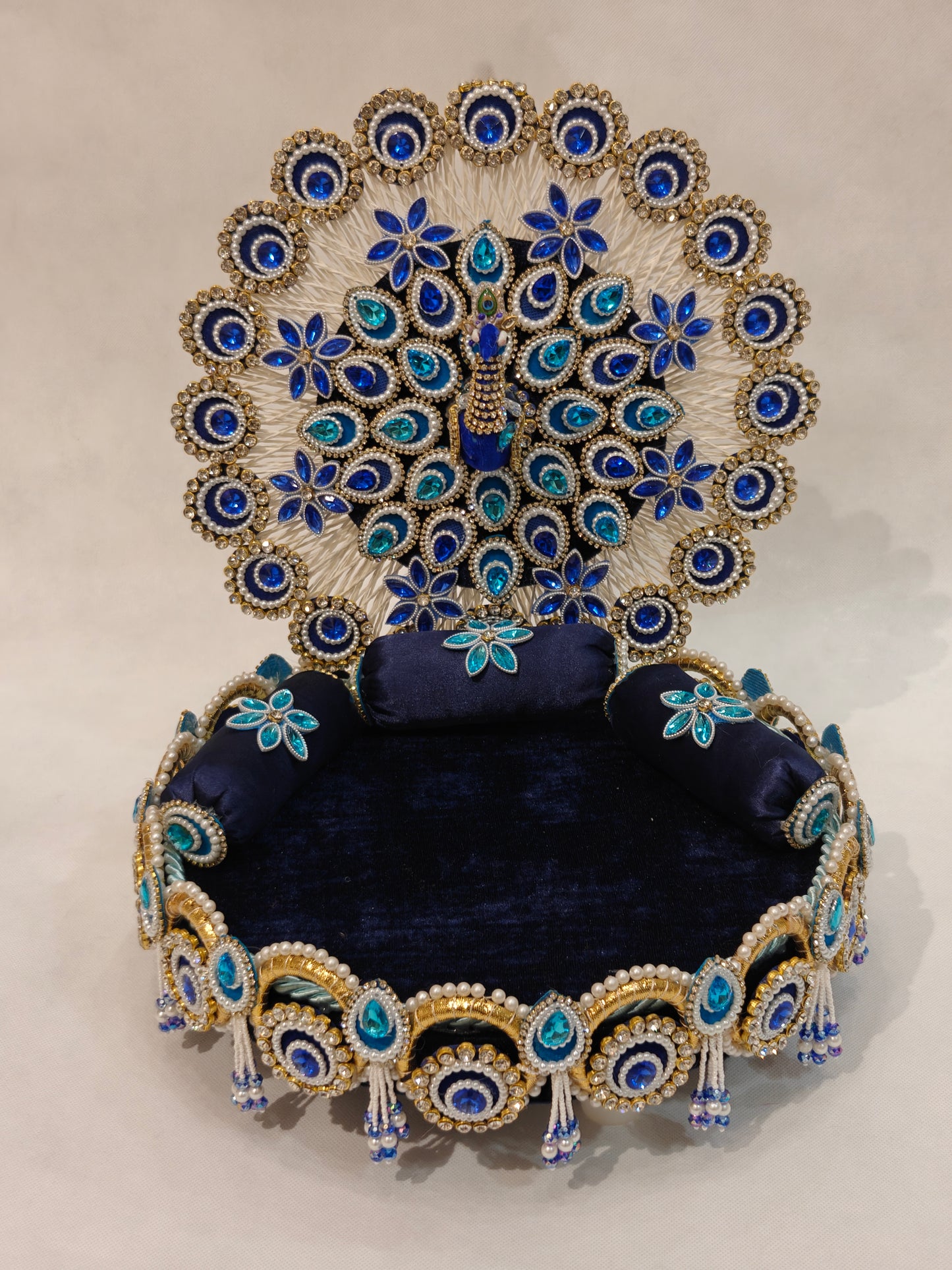 Handcrafted peacock singhaasan for Ladoo Gopal in royal blue and gold with gem embellishments, pearl beading, and detachable peacock feather backdrop — 12 inch MDF deity throne by The Wedding Station
