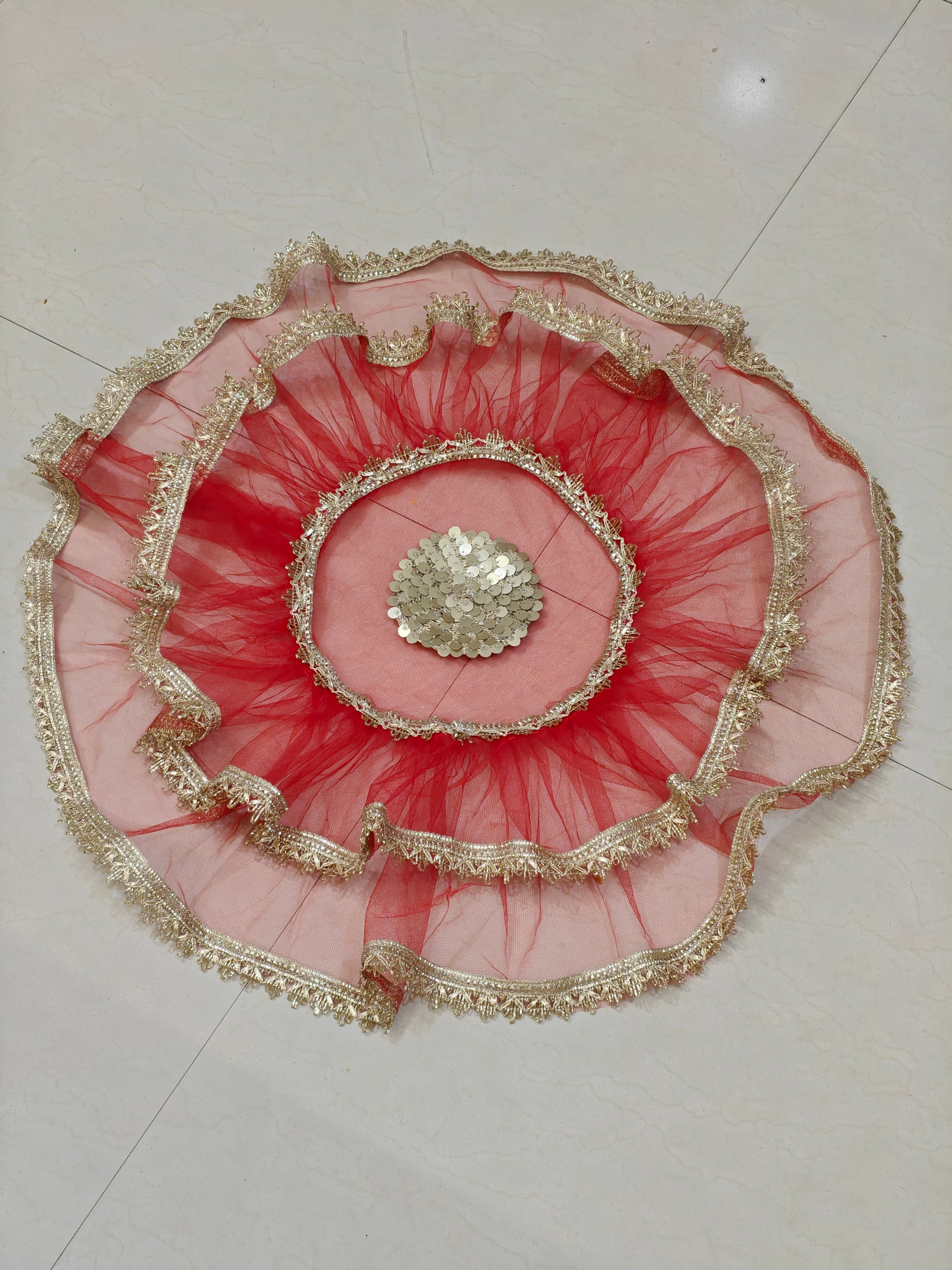 Red net thaal cover with layered ruffles, golden lace border and decorative sequin centre, 25 inches diameter.