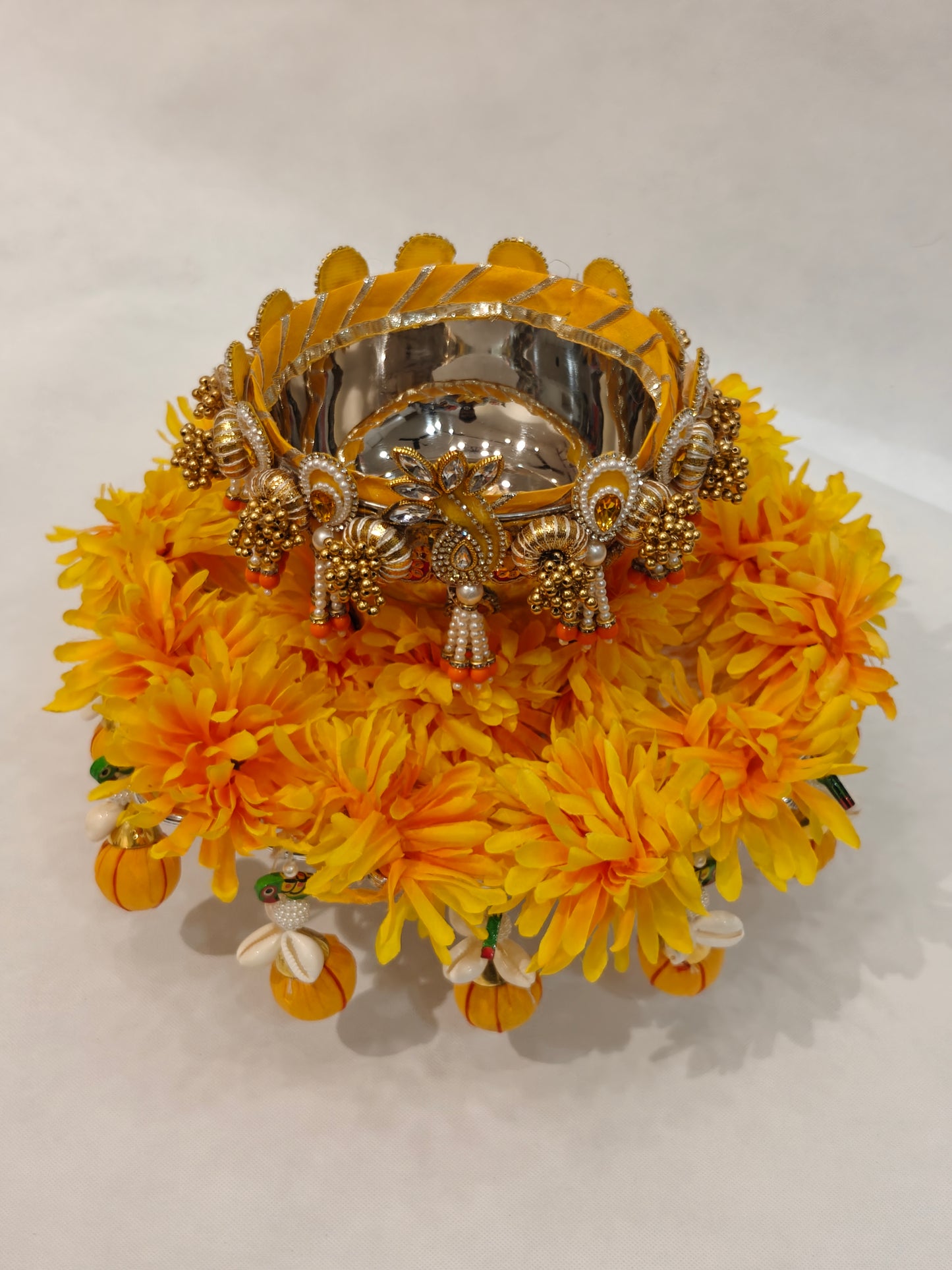 Handcrafted Haldi ceremony platter with 12-inch silver base, 6-inch metal bowl, yellow marigold flower ring, gold pearl embellished rim and orange tassel drops for wedding ritual