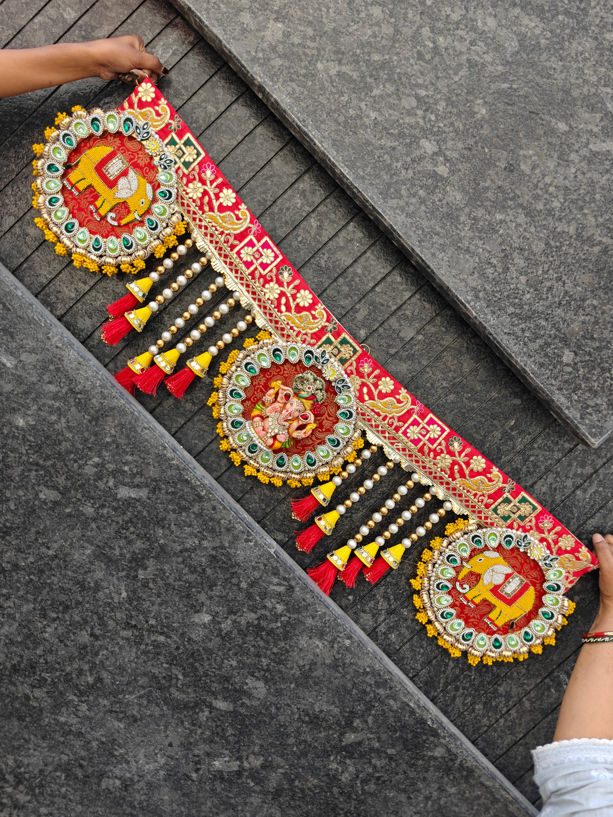 Red brocade Ganesh toran with elephant medallions, kundan stones, pearl and gold bead strings and red tassels