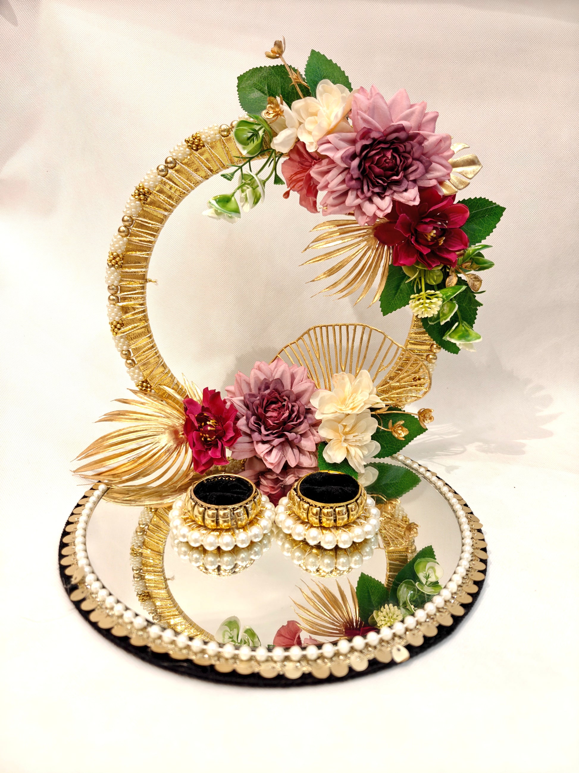 Handcrafted ring ceremony platter with 11-inch mirror MDF base, gold crescent arch, burgundy and mauve silk flowers, pearl-bordered tray, and two pearl ring holders — by The Wedding Station