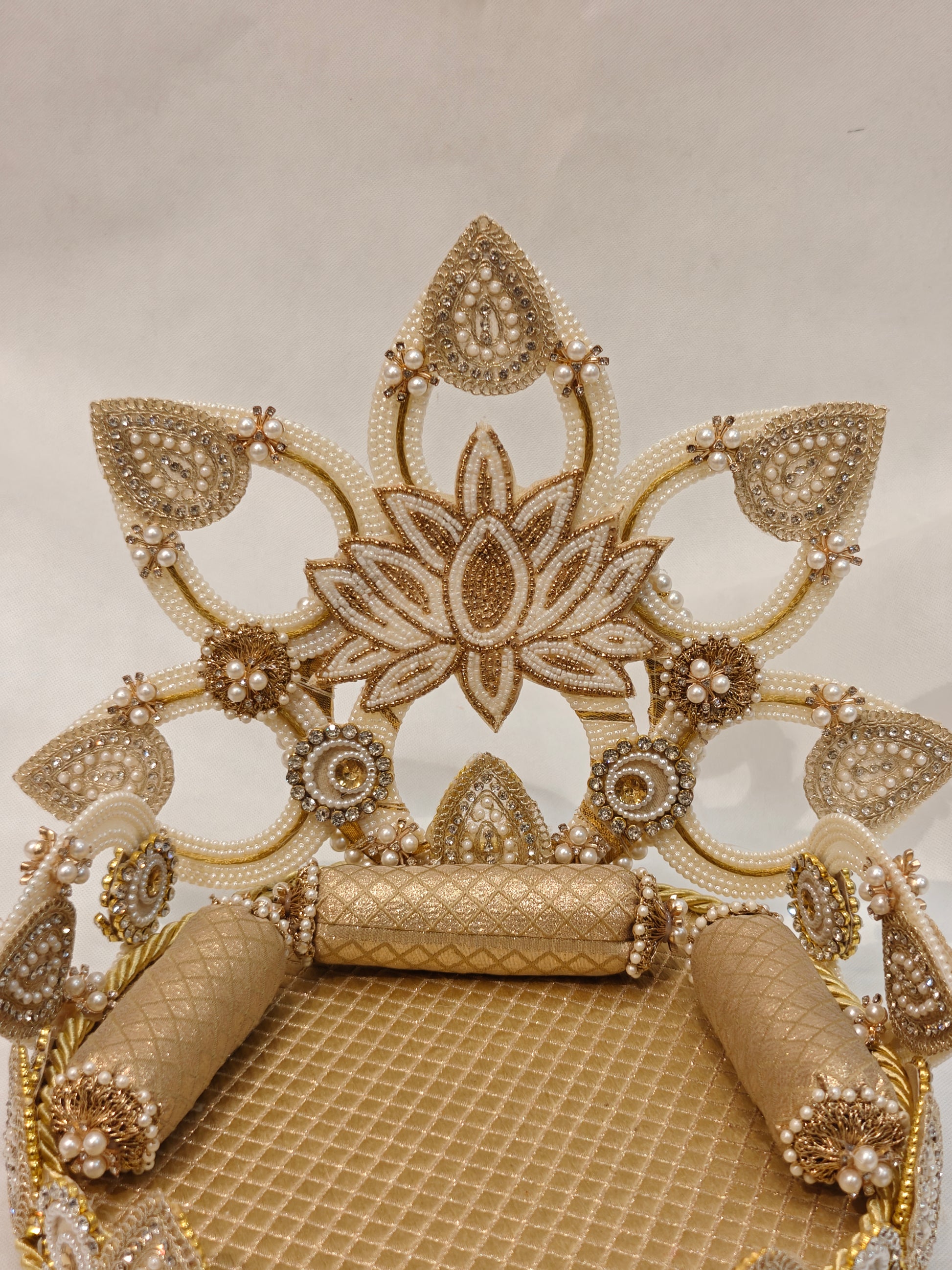 Close-up of gold lotus Singhaasan backdrop for Ladoo Gopal — ivory pearl beaded open-fret lotus crown, rhinestone medallions, gold quilted seating and bolster cushions by The Wedding Station