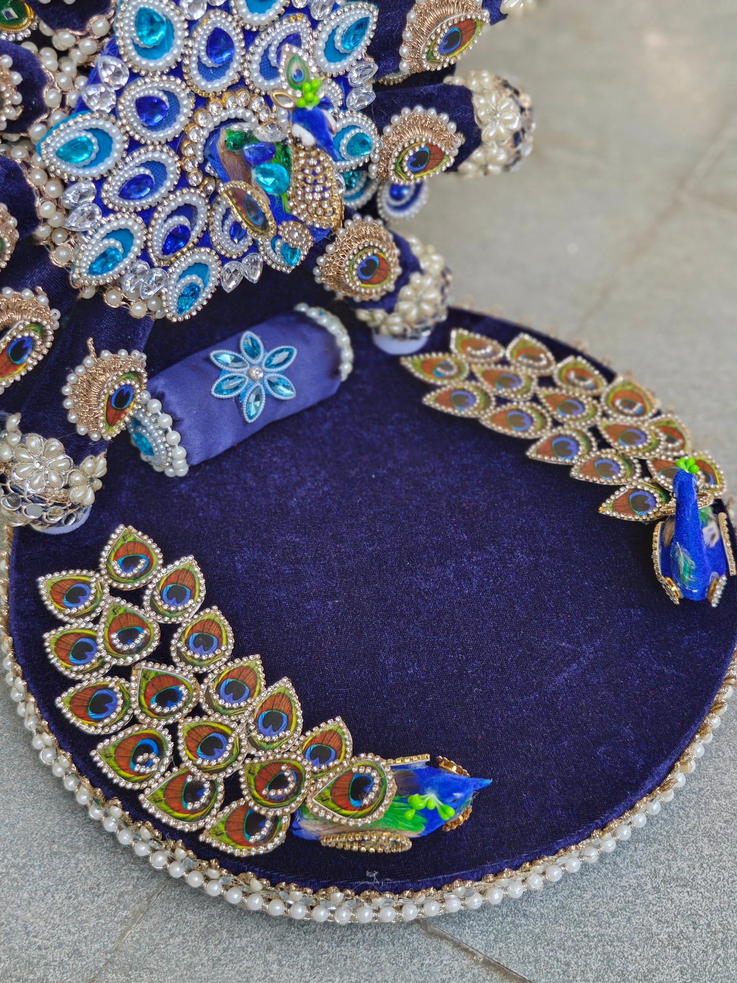 Close-up of peacock singhasan velvet aasan with hand-embroidered peacock motifs, real feathers, rhinestones and double pearl border