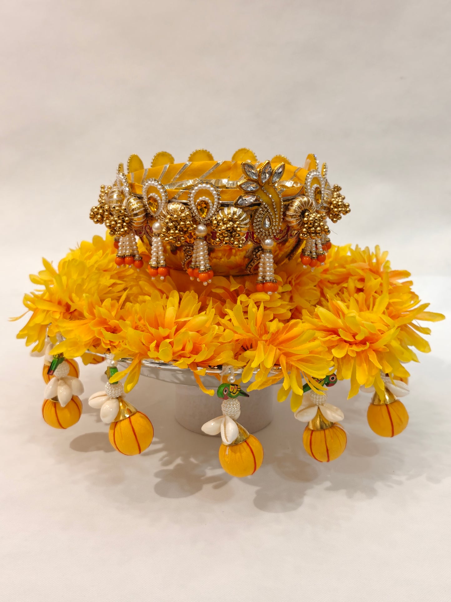 Handcrafted Haldi ceremony platter with 12-inch silver base, 6-inch metal bowl, yellow marigold flower ring, gold pearl embellished rim and orange tassel drops for wedding ritual