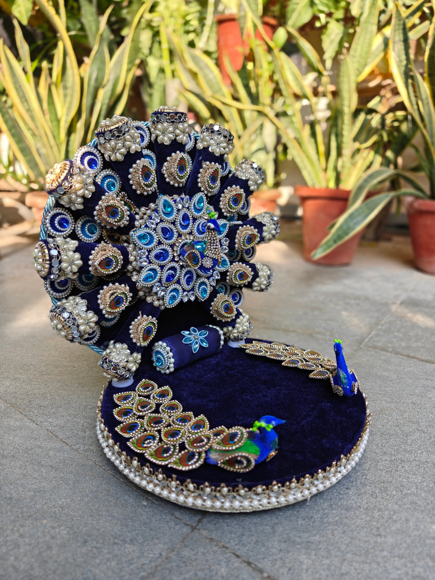 Side angle view of handcrafted peacock singhasan for Bal Gopal with velvet fan backrest, satin bolster cushion and pearl-bordered circular seat