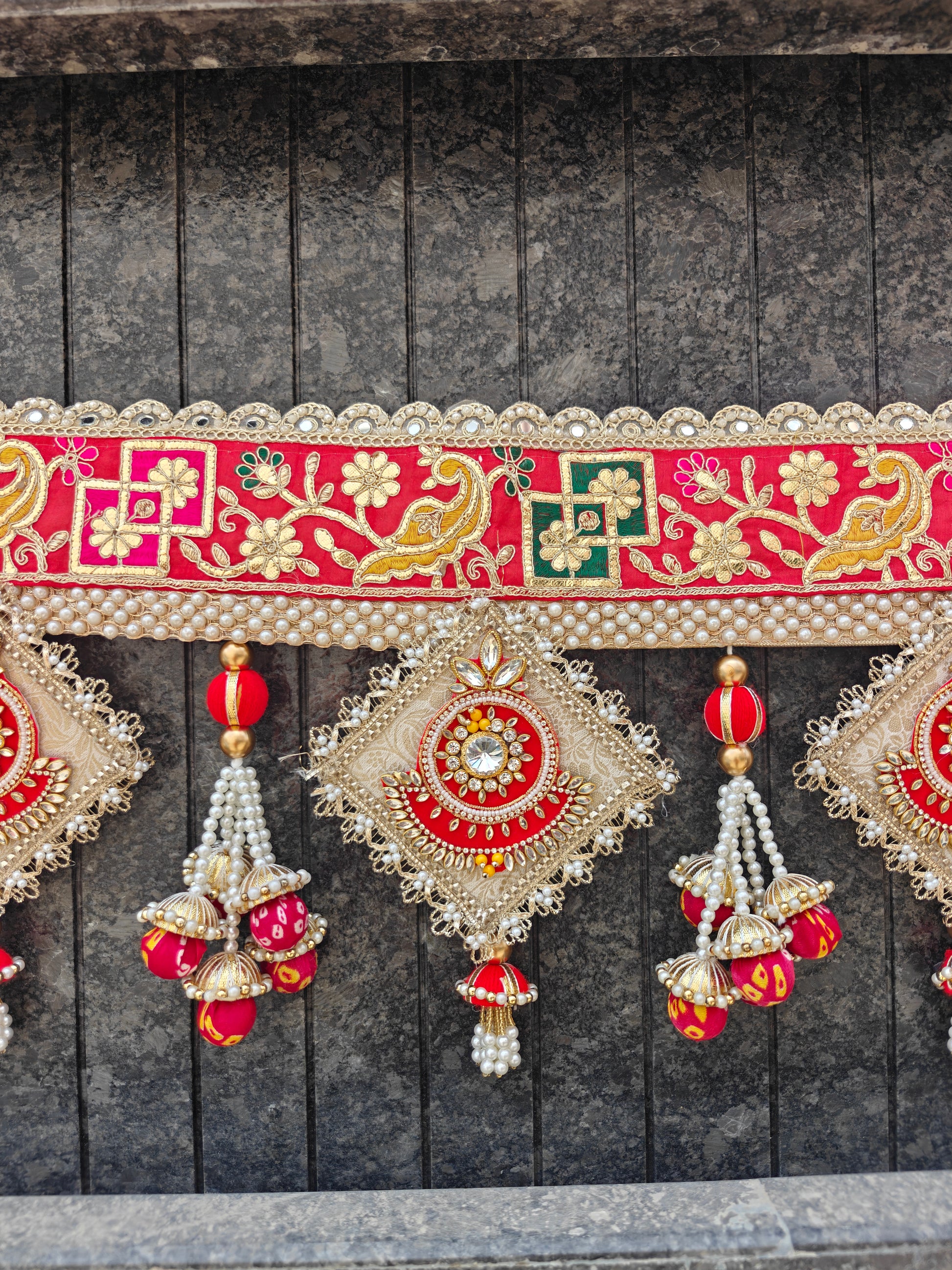"Red gold gota patti bandhanwar close-up with kundan diamond pendant and pearl jhumki tassel"