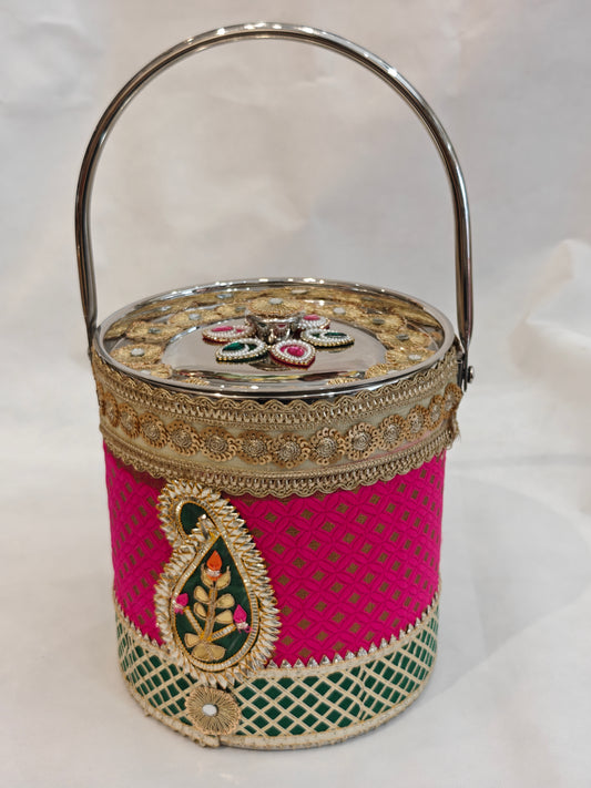 Decorated stainless steel bucket with arched handle for Indian wedding trousseau in hot pink and green brocade with gold diamond lattice, kundan paisley appliqué, gold zari scalloped lace and mirror-finish lid with gold zardozi sunflower medallions — 8.25 inch diameter, 9 inch height