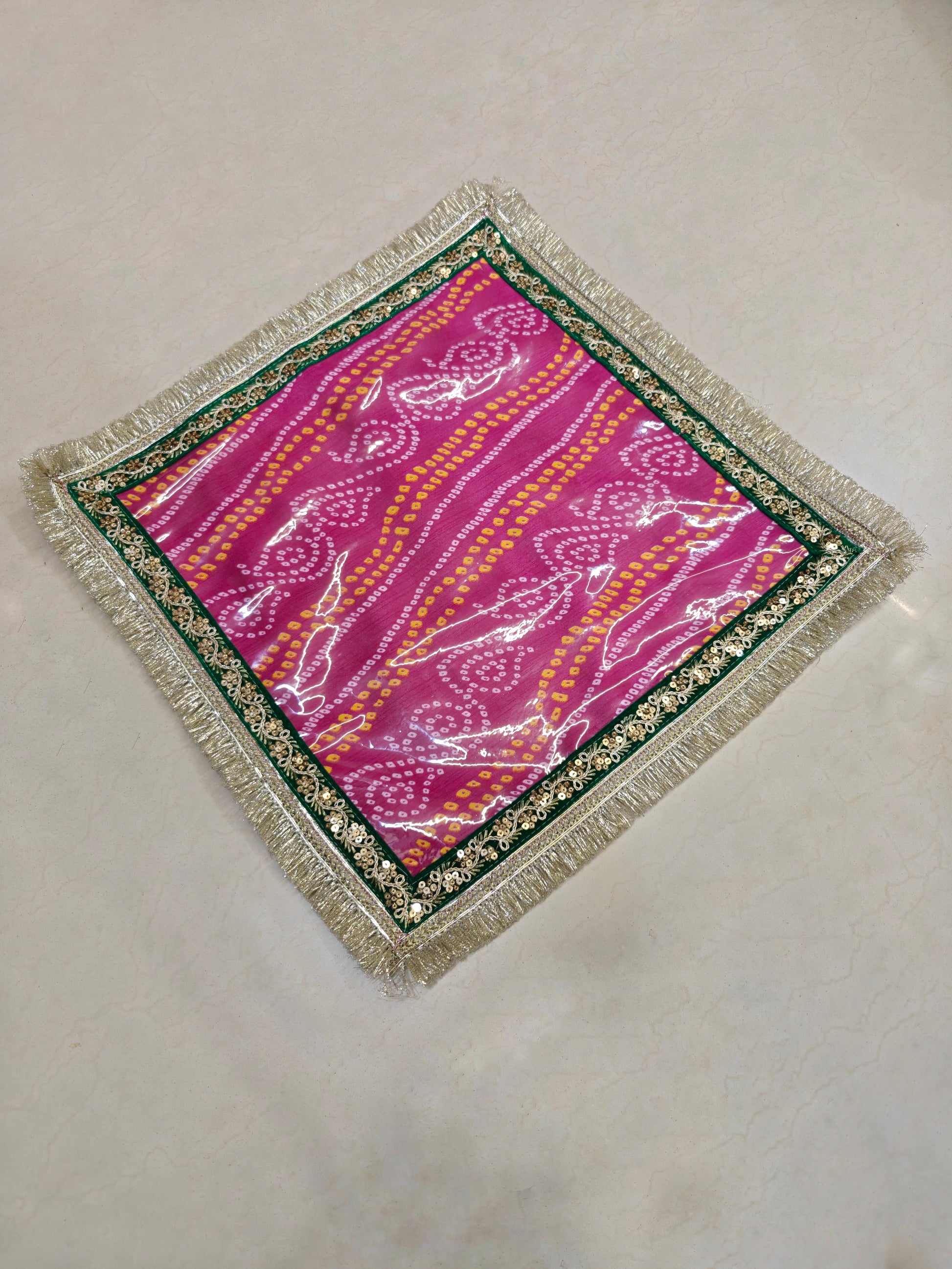 Pink Bandhani Dupion silk mangodi mat with transparent PVC sheet, gold sequin border and silver zari fringe, 20x20 inches, for Indian wedding rituals