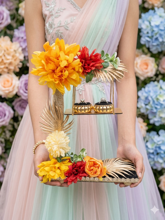 2-tier handcrafted wooden ring ceremony stand with yellow, red, and orange silk flowers, gold palm leaves, jute-wrapped column, swing shelf, and two gold ring holders — by The Wedding Station