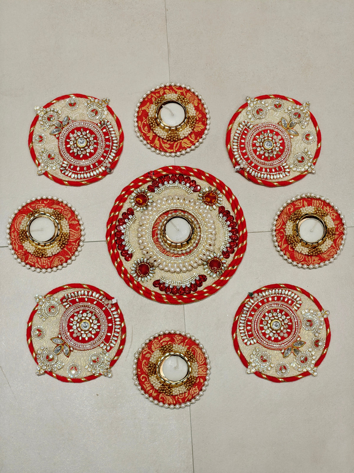 Red and gold brocade rangoli set with jewel-encrusted centrepiece and tealight holders