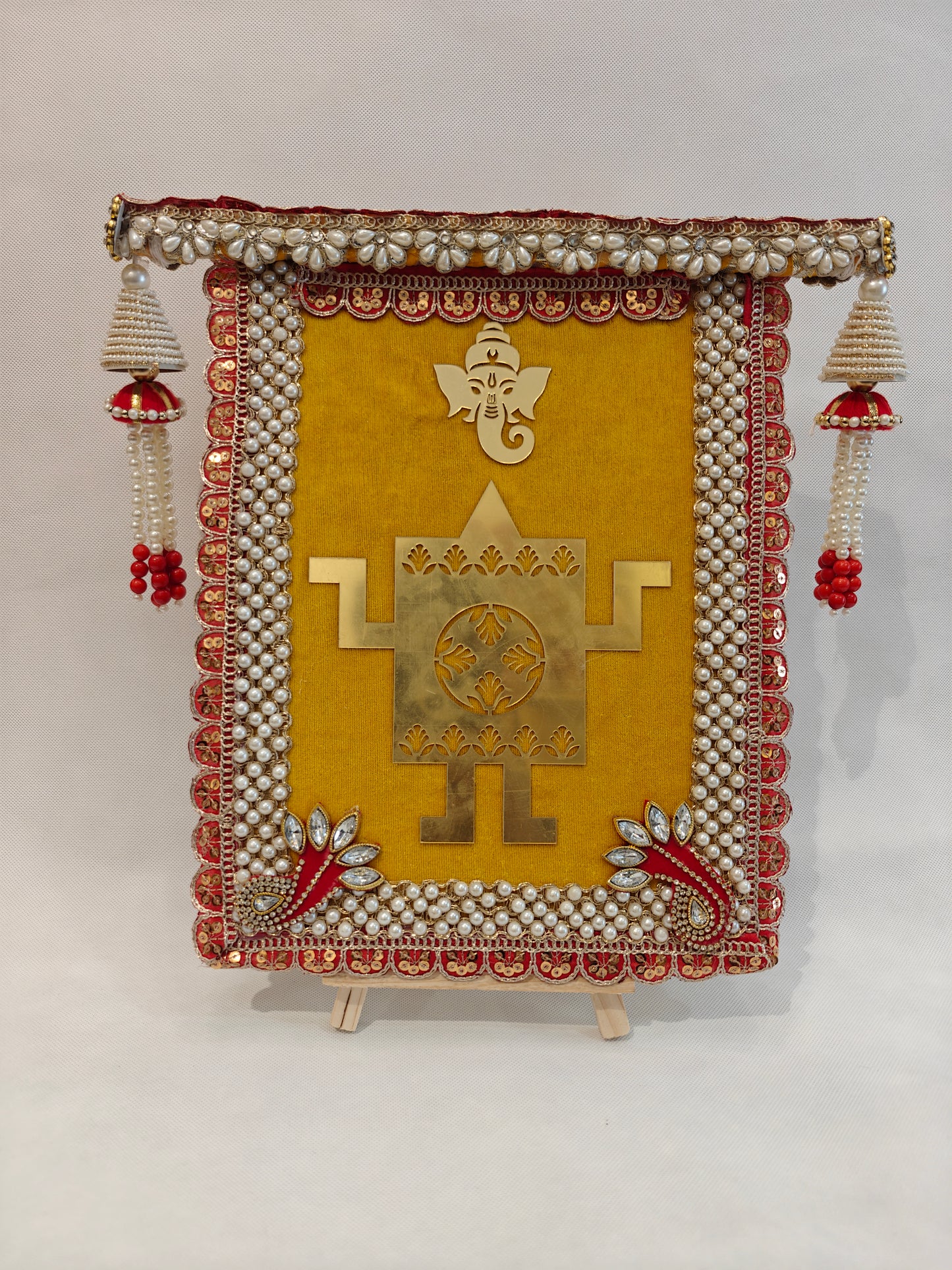 yellow velvet wedding thaapa devta frame with gold Ganesh Swastik, red sequin pearl border and white bead jhumki tassels for Hindu wedding ritual