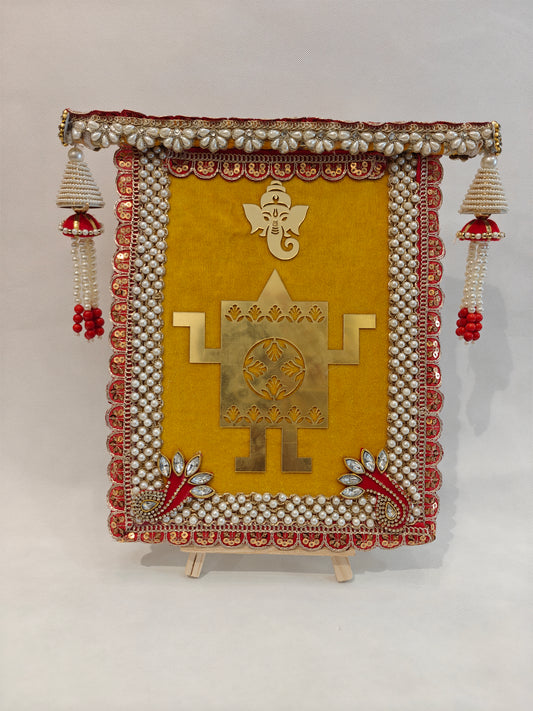 yellow velvet wedding thaapa devta frame with gold Ganesh Swastik, red sequin pearl border and white bead jhumki tassels for Hindu wedding ritual