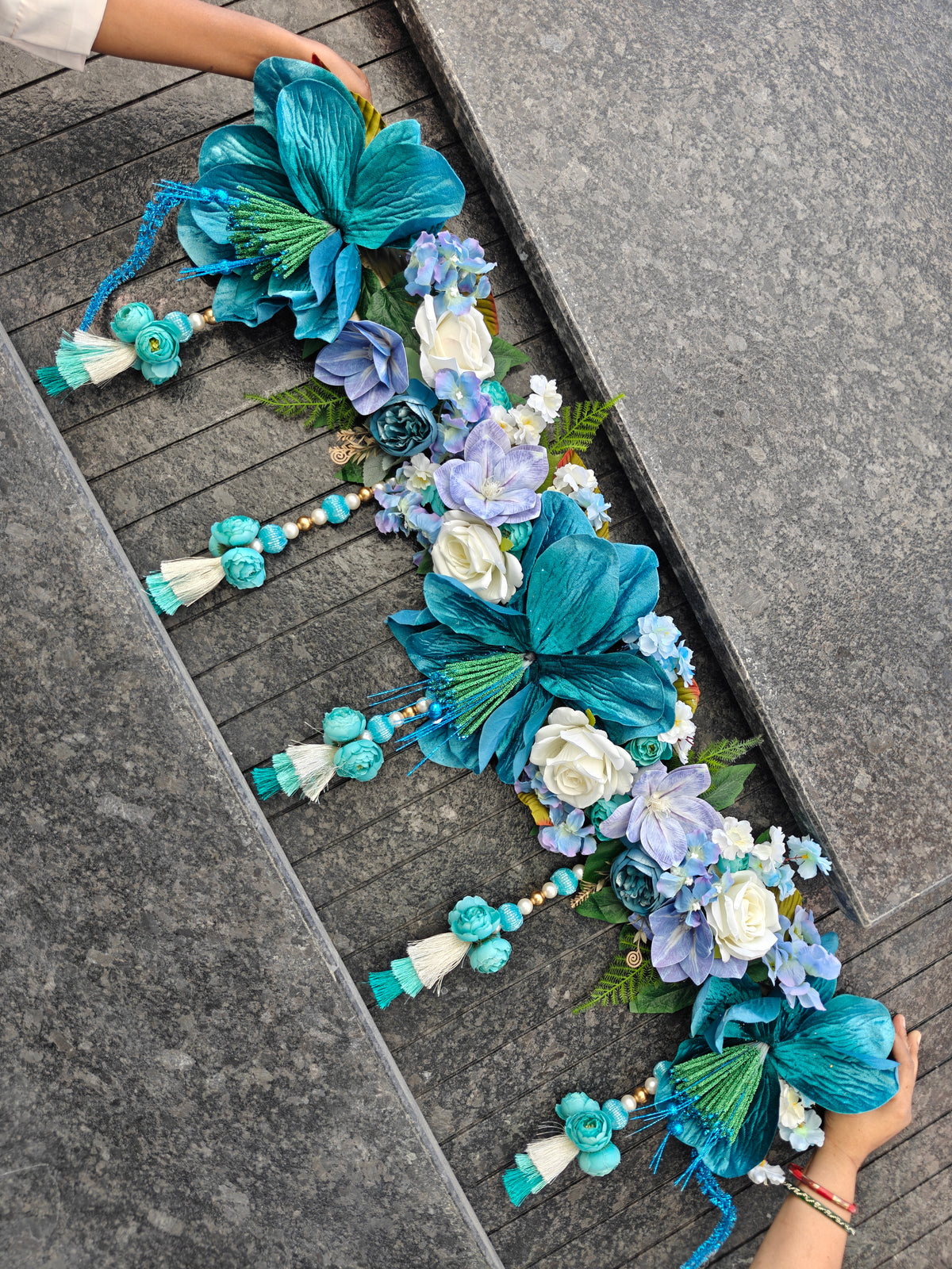 Teal and blue floral toran with white roses, blue hydrangeas, ferns and pearl latkans with teal tassels