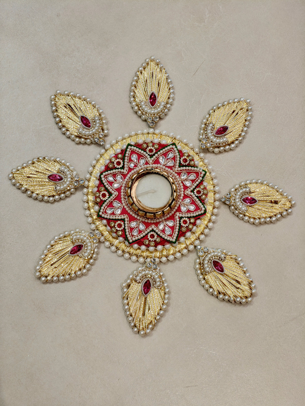 Golden peacock feather motif rangoli with red kundan centre and tealight holder