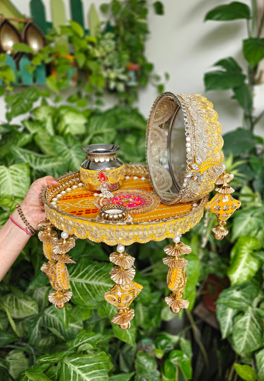 Yellow and gold Karva Chauth thali set with decorated steel thali, ornate steel kalash, candle, decorated channi, pearl detailing and hanging festive latkans