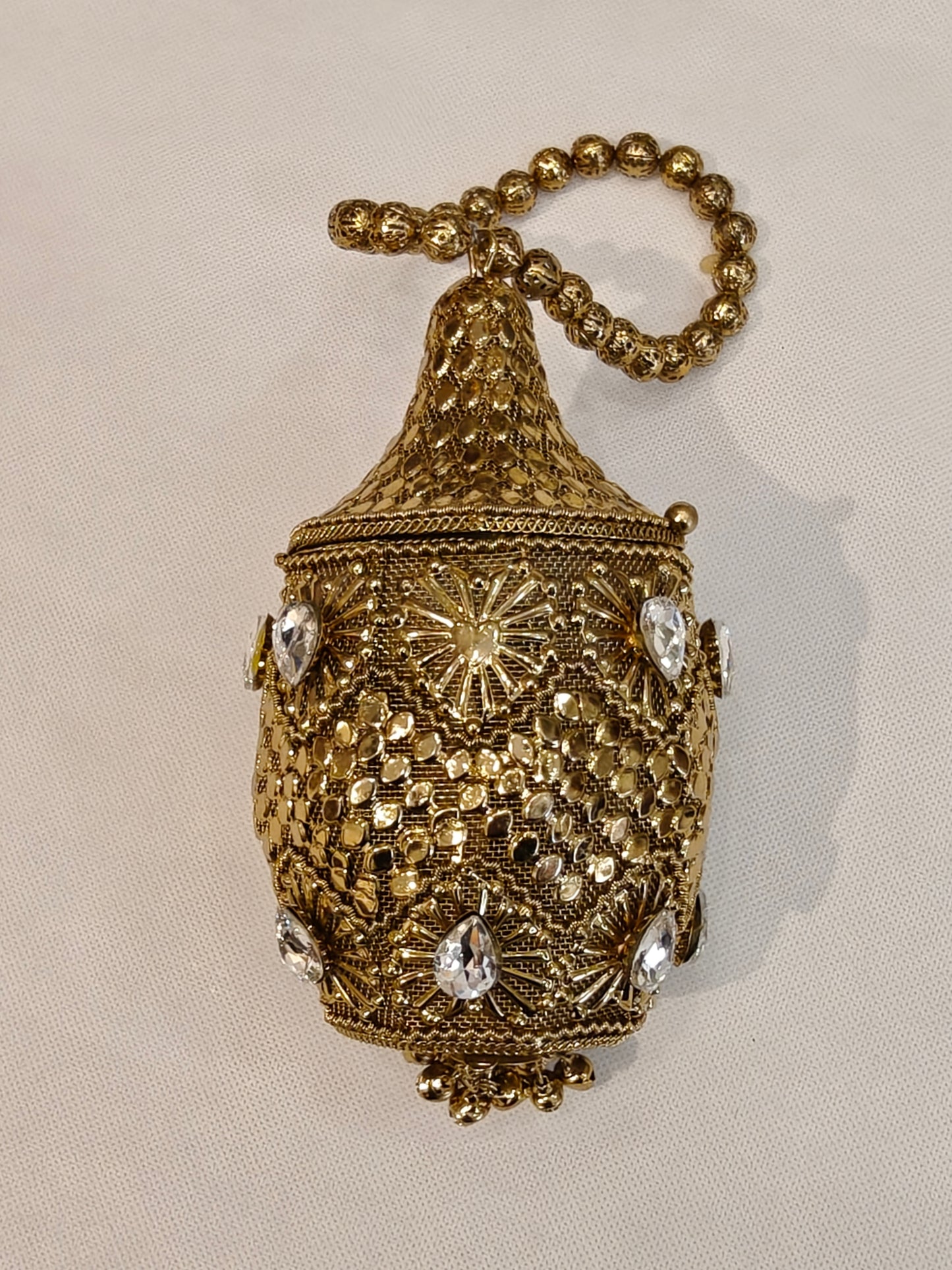 Handcrafted gold brass lantern-shaped potli bag with conical lid, teardrop crystal stones, starburst filigree motifs, scalloped petal base and filigree bead loop handle — bridal wedding potli by The Wedding Station Meerut