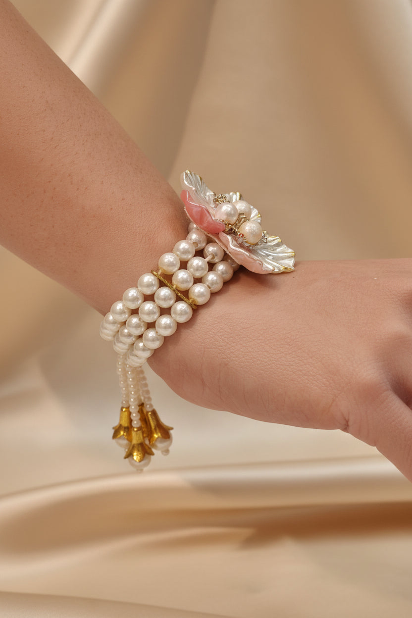 Floral pearl bracelet with pastel enamel petals in pink, white, and champagne, pearl centres, crystal accents, and triple-strand pearl band — bridal jewellery by The Wedding Station