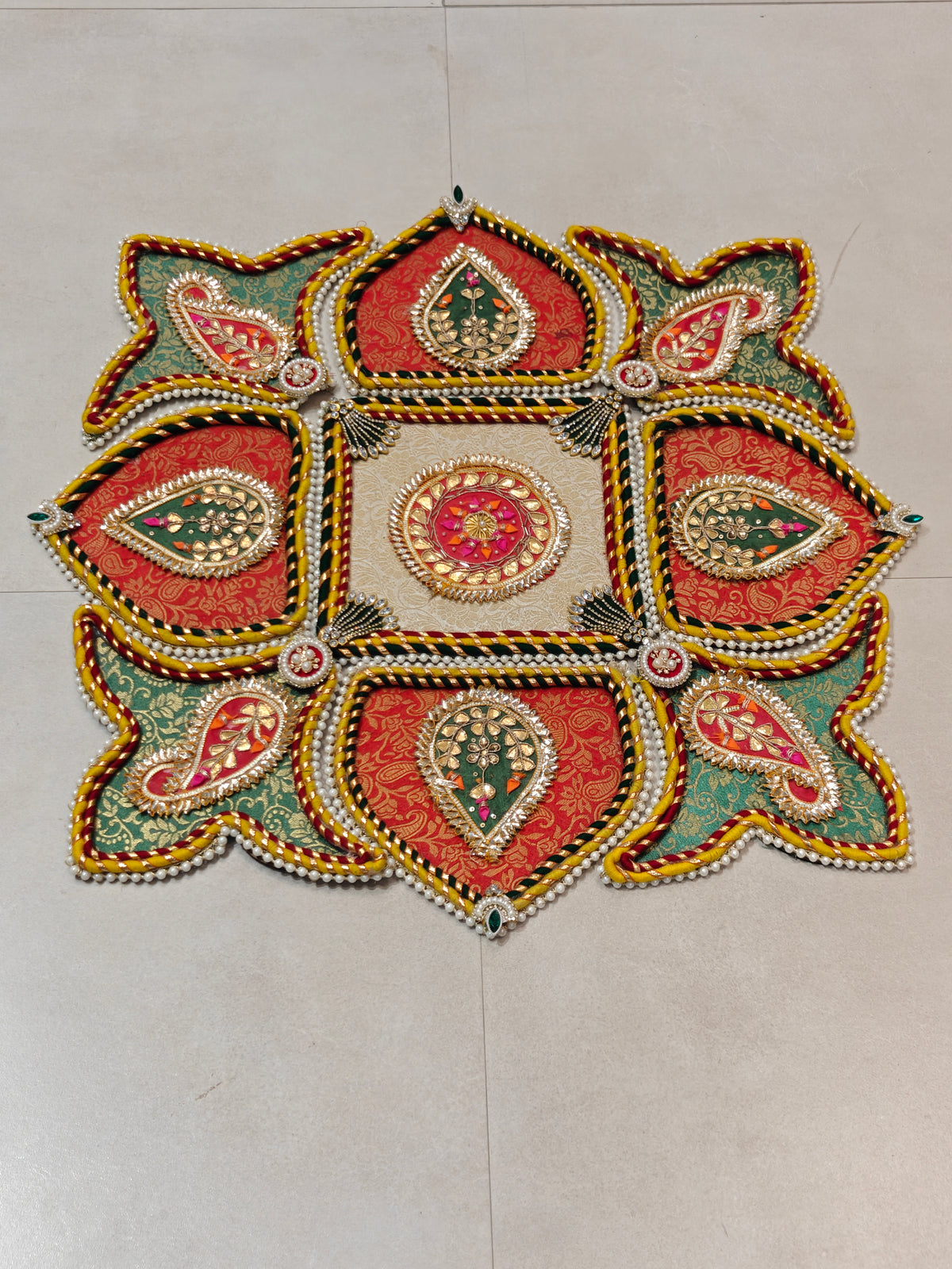 Multicolour brocade star-shaped rangoli with gold paisley motifs and pearl trim