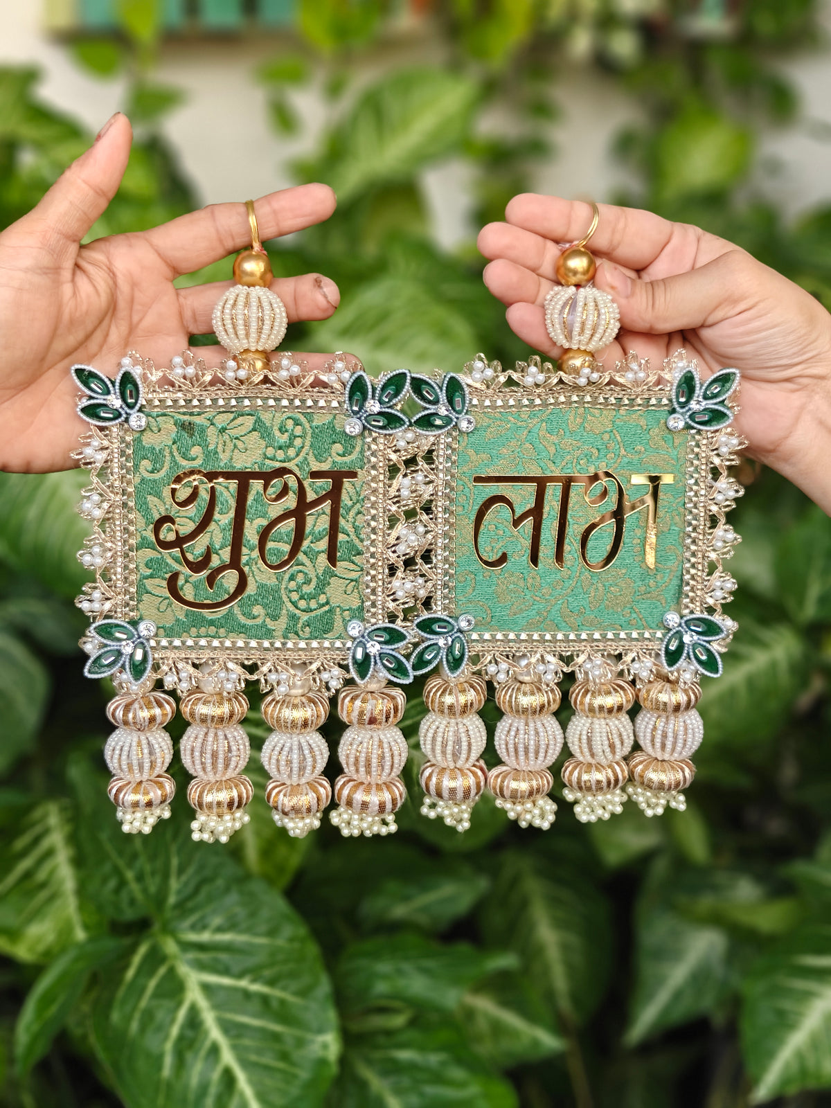 Pair of green brocade Shubh Labh hangings with gold lettering, gota patti border, green leaf corner motifs and pearl latkans