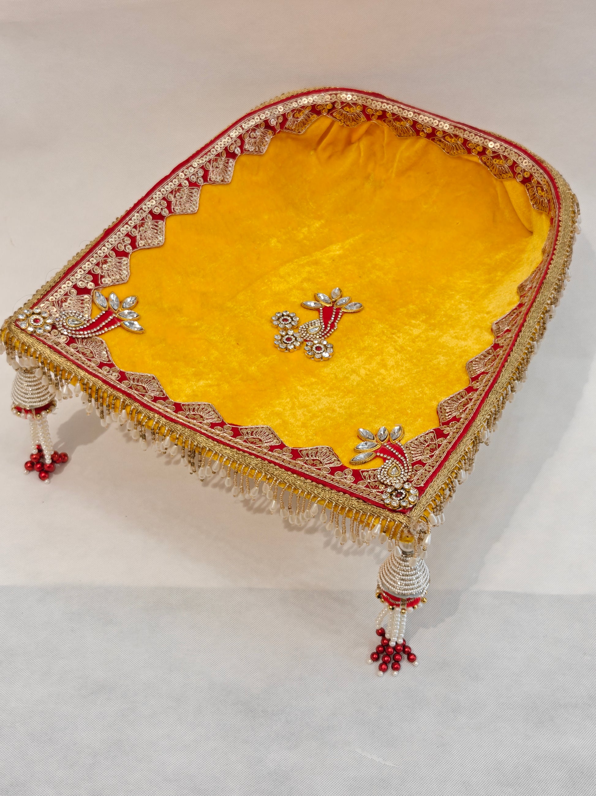 Large yellow velvet soupda 12x13 inch with red zari border, crystal peacock appliqué and white bead tassel drops — handcrafted Indian wedding ceremony tray by The Wedding Station