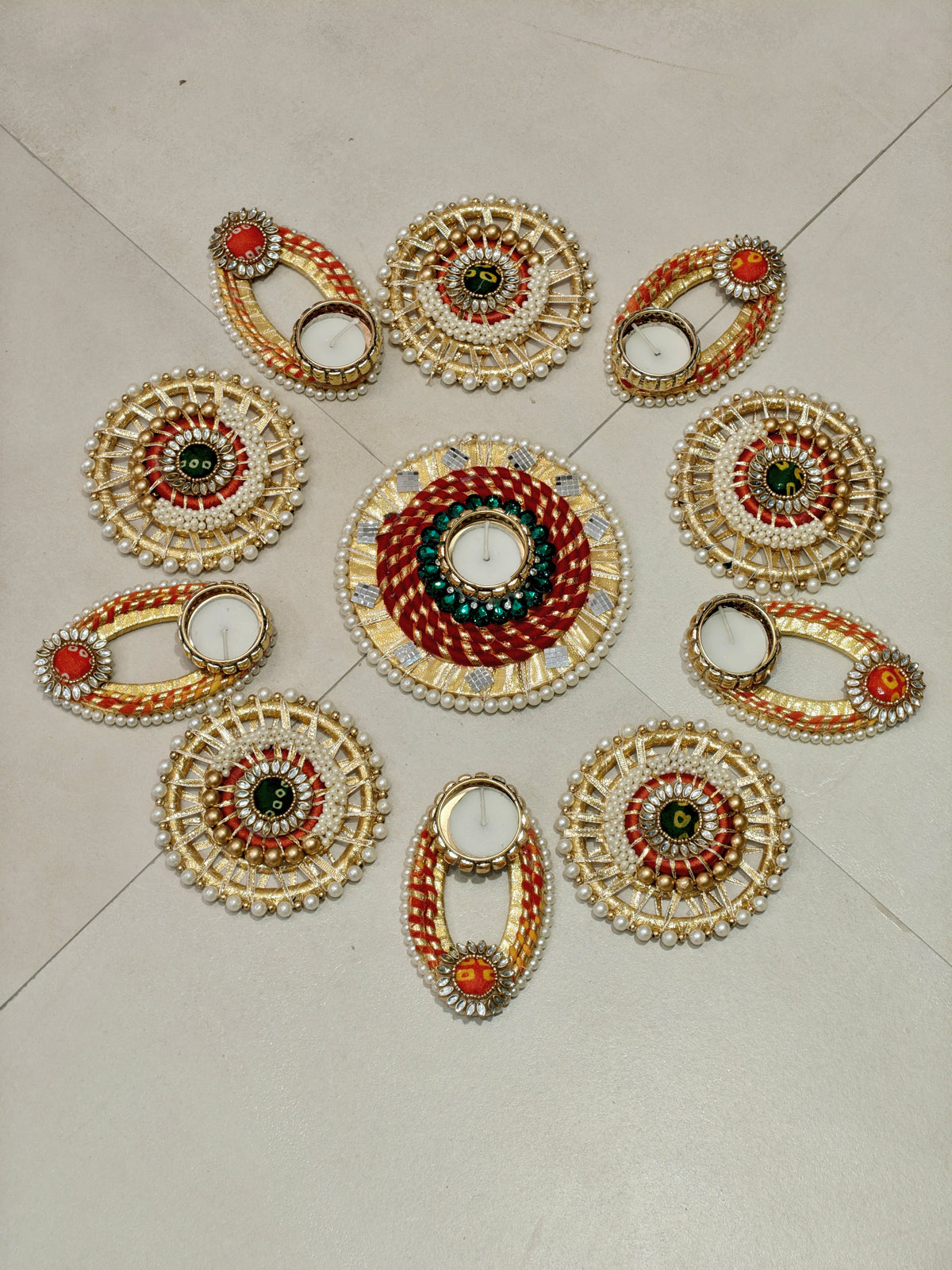 Red and gold spiral rangoli set with kundan discs and loop tealight holders