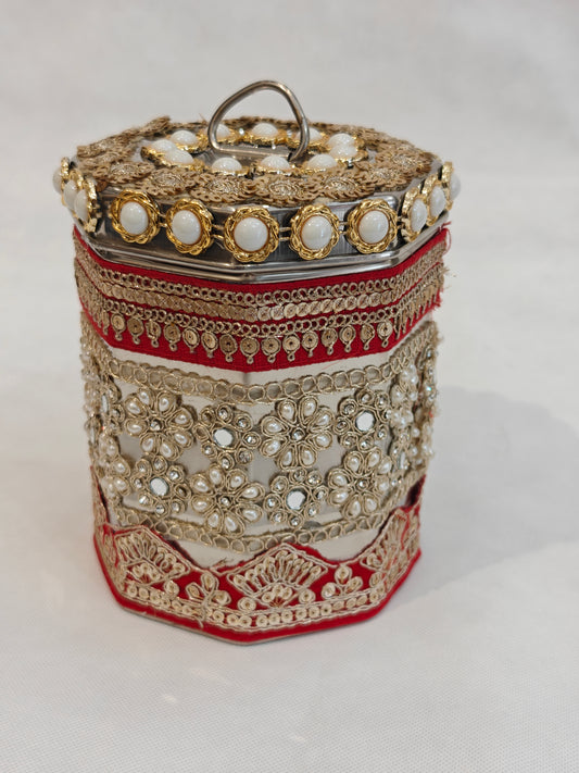Decorated octagonal stainless steel storage box for Indian wedding with red velvet gold zari lace upper band, mirror-work floral pearl cluster mid section, red gold fan motif base border and pearl cabochon lid with steel D-ring handle — 5x5 inch, 6.25 inch height