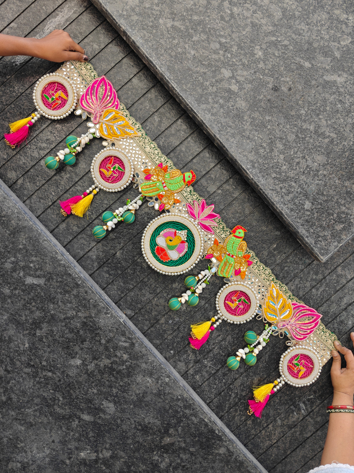 Multicolour toran with embroidered parrots, lotus, swastik medallions, mirror-work lace and pink and yellow tassels