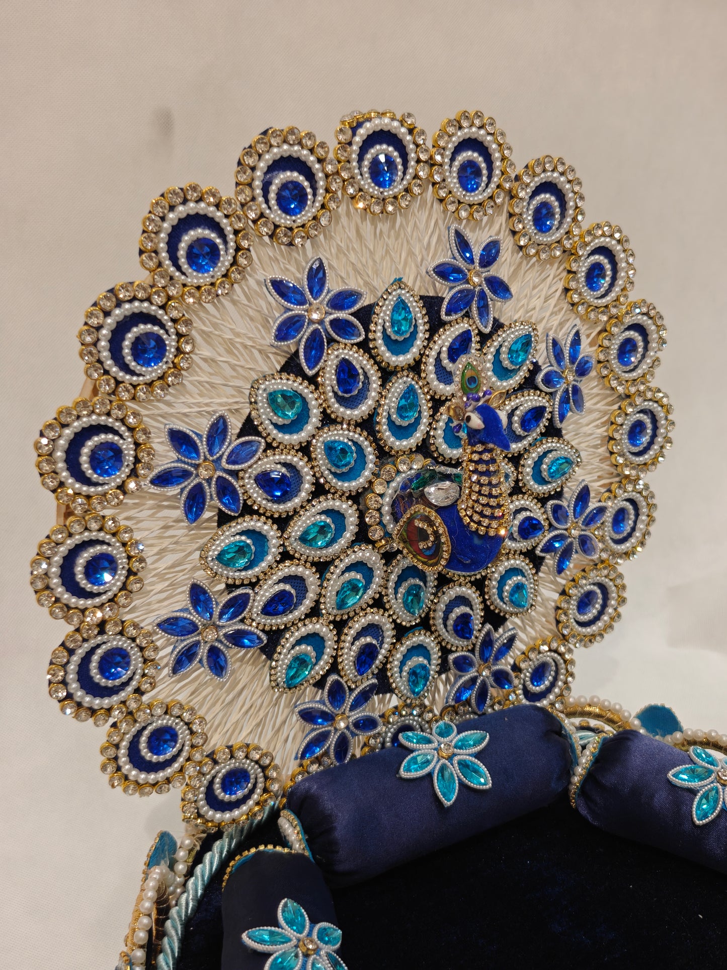 Handcrafted peacock singhaasan for Ladoo Gopal in royal blue and gold with gem embellishments, pearl beading, and detachable peacock feather backdrop — 12 inch MDF deity throne by The Wedding Station