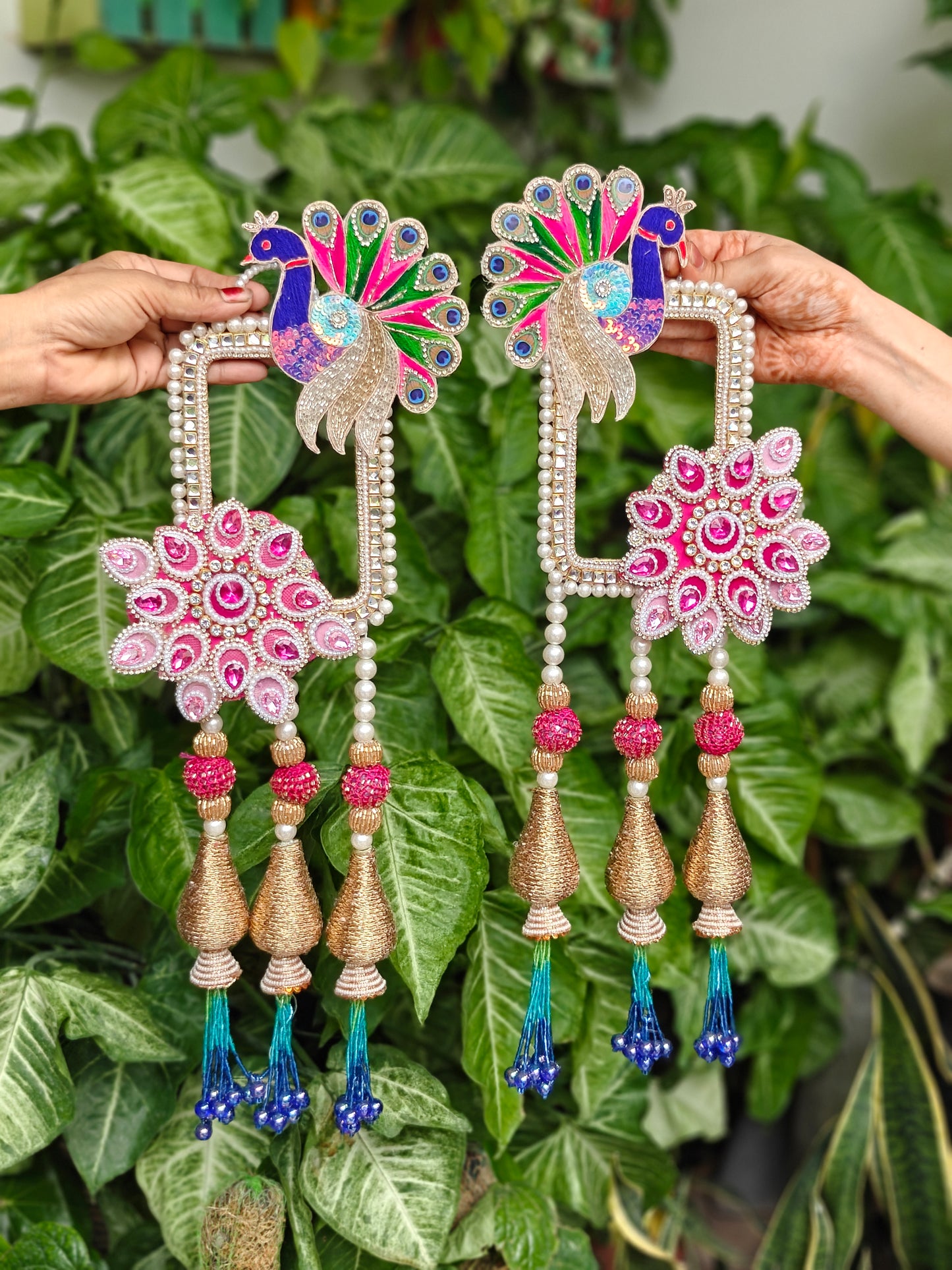 Peacock Diwali hanging with pink floral embellishments, pearl detailing, gold tassels and blue bead accents