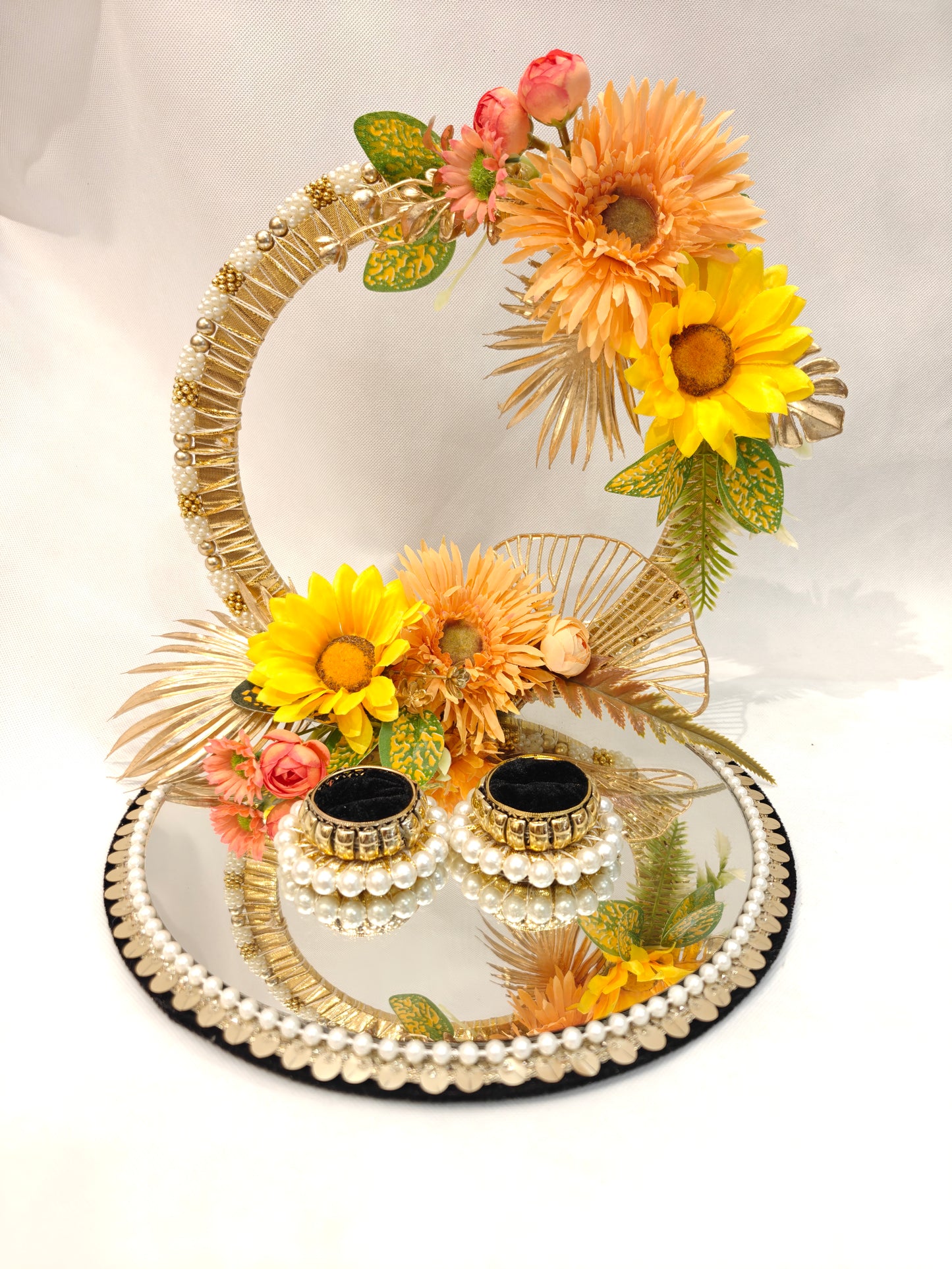 Handcrafted ring ceremony platter with 11-inch mirror MDF base, gold crescent arch, yellow sunflowers, peach gerberas, blush roses, pearl-bordered tray, and pearl ring holders — by The Wedding Station
