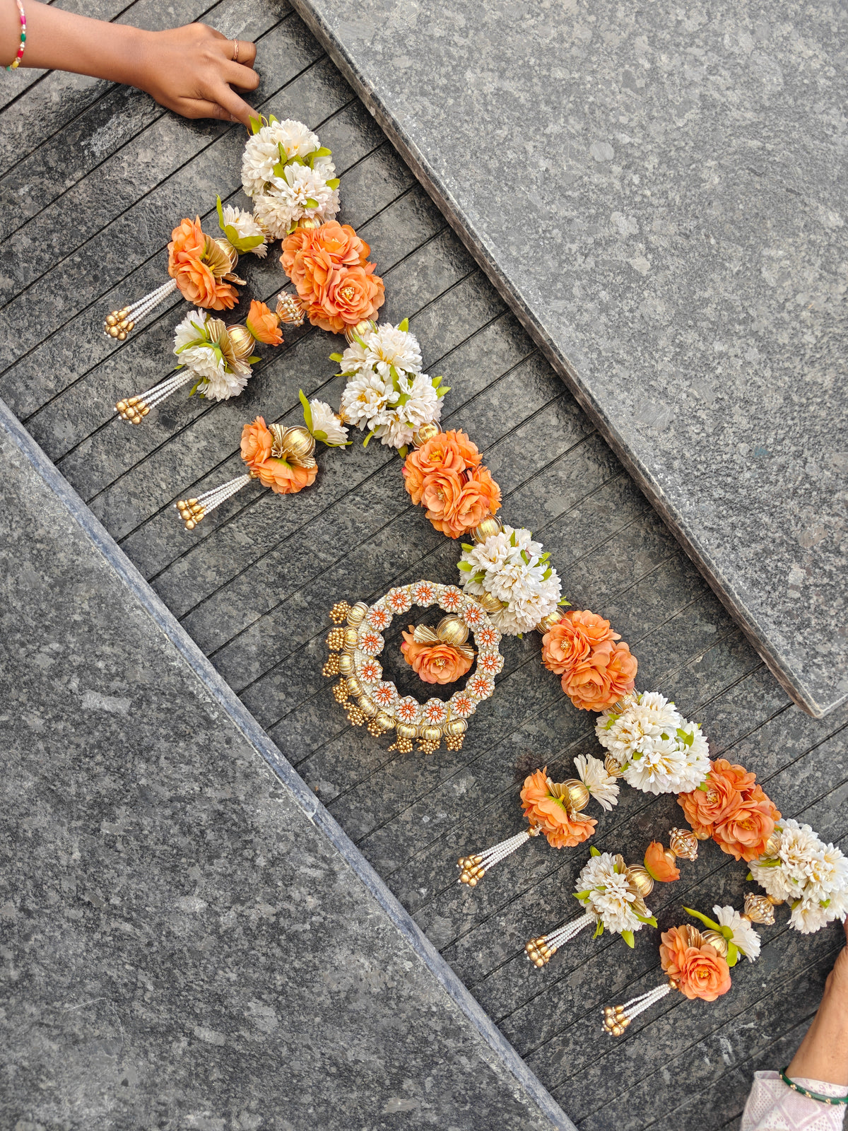 Orange and white floral toran with gold gota balls, central stone-studded ring and pearl bead latkans
