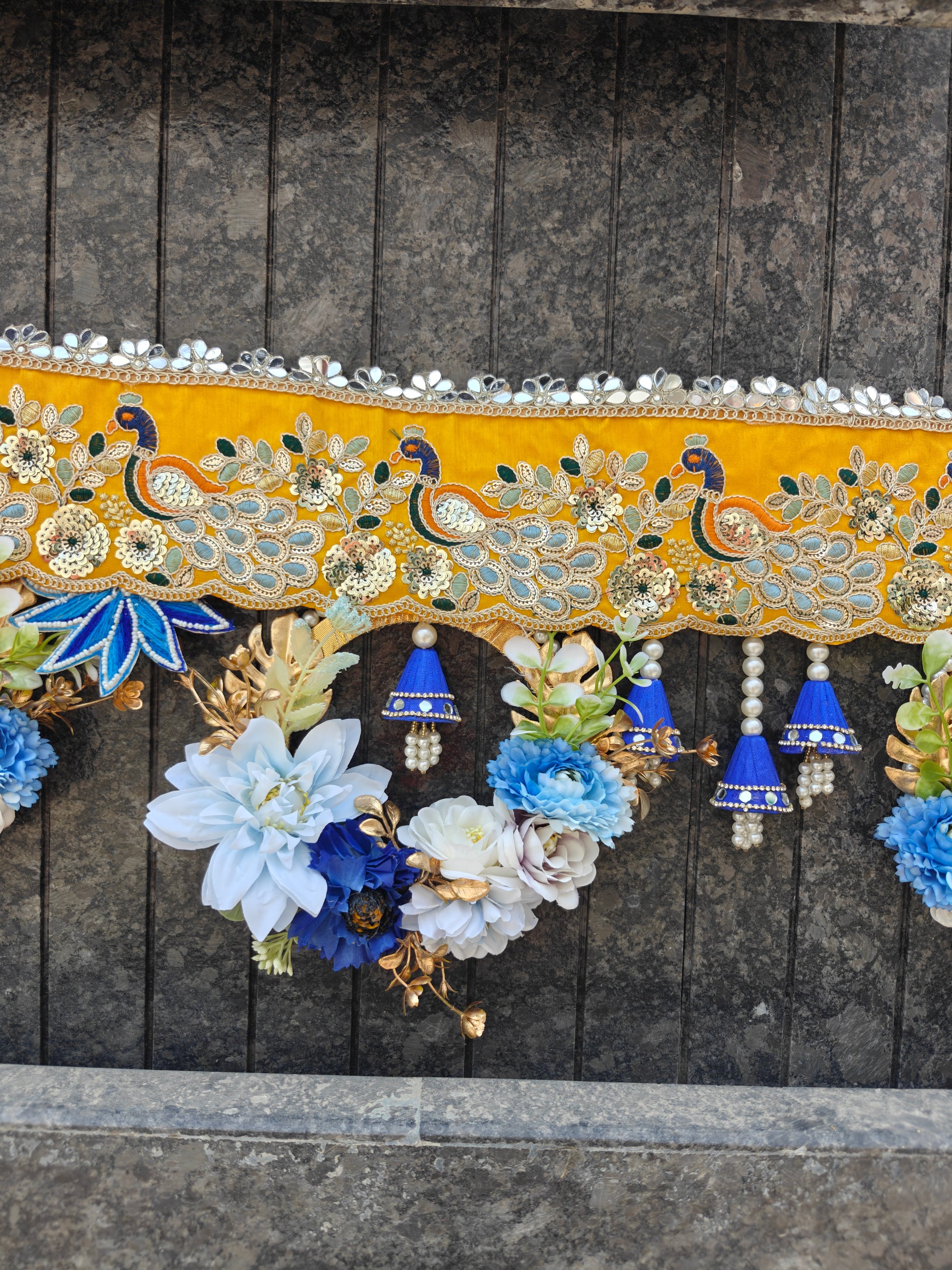 Close-up of peacock motif embroidery on wedding door toran