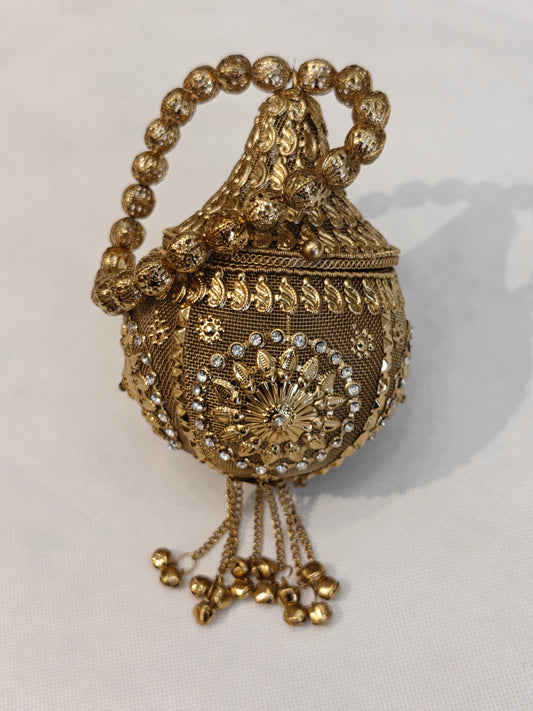 Handcrafted gold brass mesh round potli bag with crystal rhinestones, raised paisley motifs, floral sunburst medallion, ghungroo bell chain tassels and filigree bead loop handle — bridal wedding potli by The Wedding Station Meerut