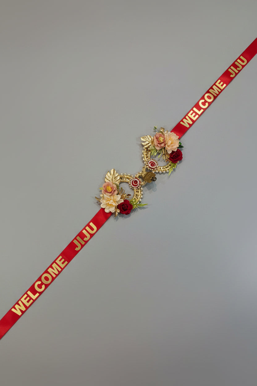 Bride's sisters welcoming groom with Welcome Jiju red floral lock ribbon at mandap entry during Indian wedding ceremony