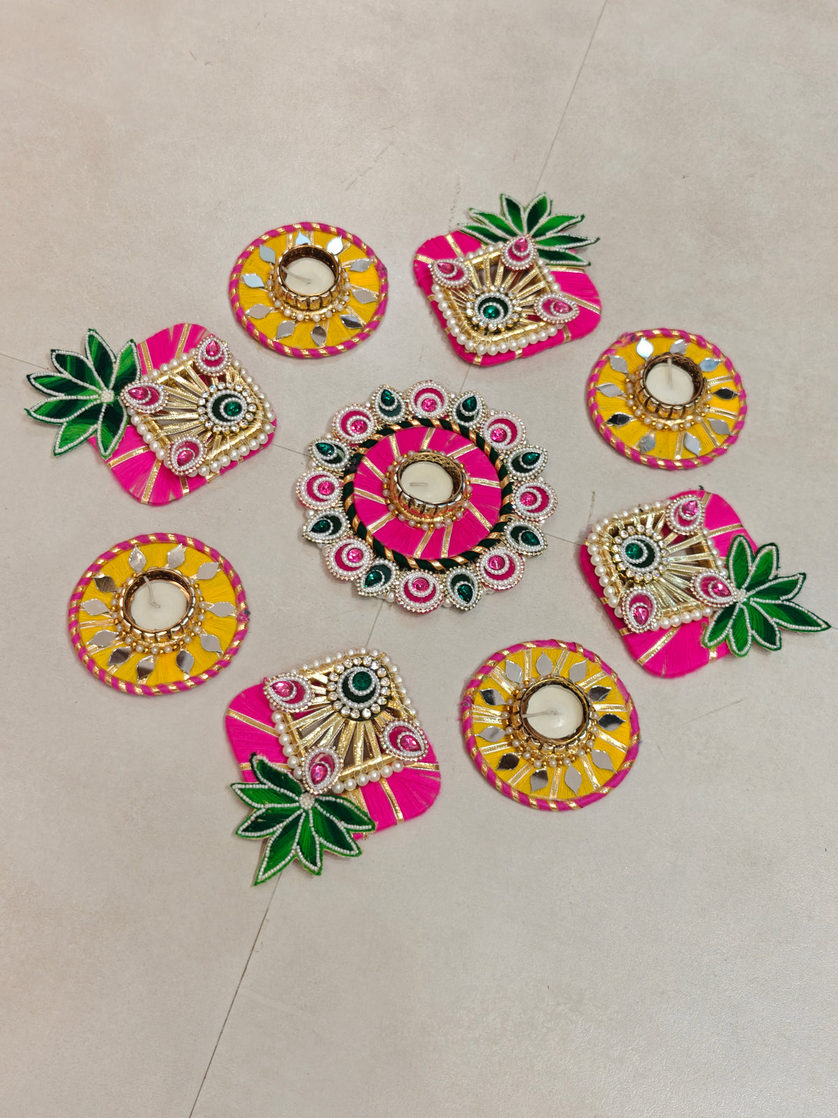 Pink and yellow leaf motif rangoli set with mirror work and tealight holders